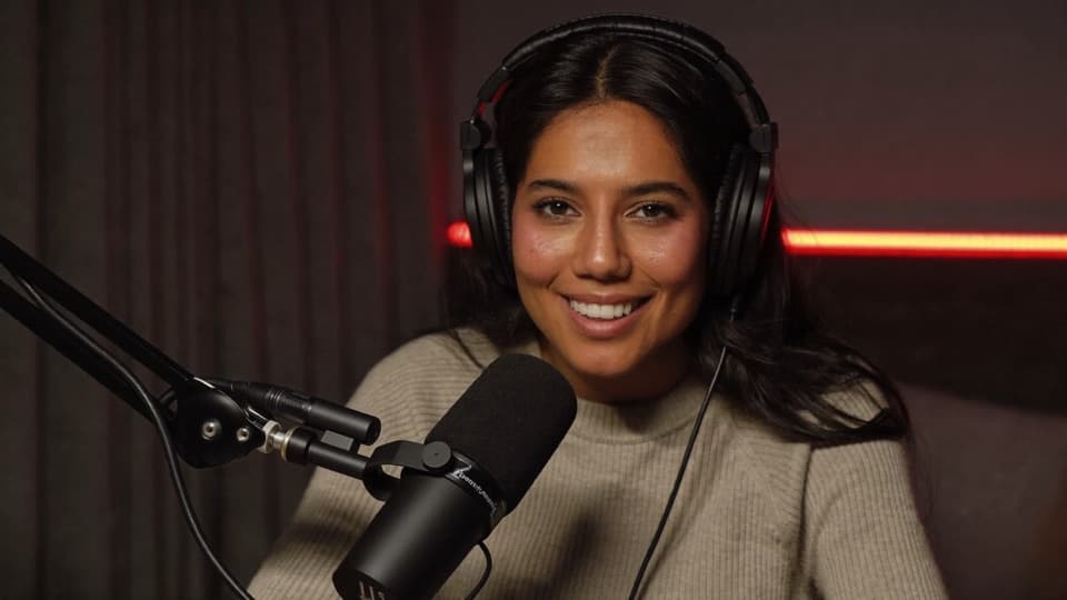 Podcast host on webcam in a dark studio with red accent lighting